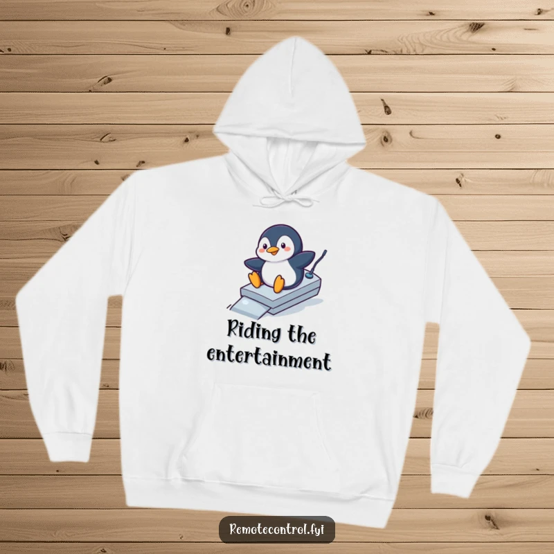 Funny penguin hoodie showing a playful penguin sliding down a remote control like a ramp, a humorous and cozy garment.
